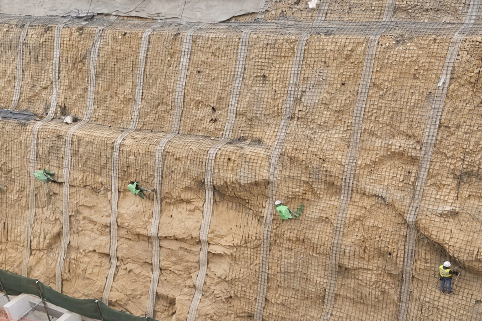 Estabilización de talud con malla, anclajes y personal técnico en obra
